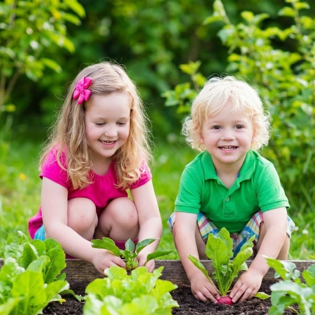 Two young children smile as they tend a small garden together, showing environmental stewardship and citizenship.